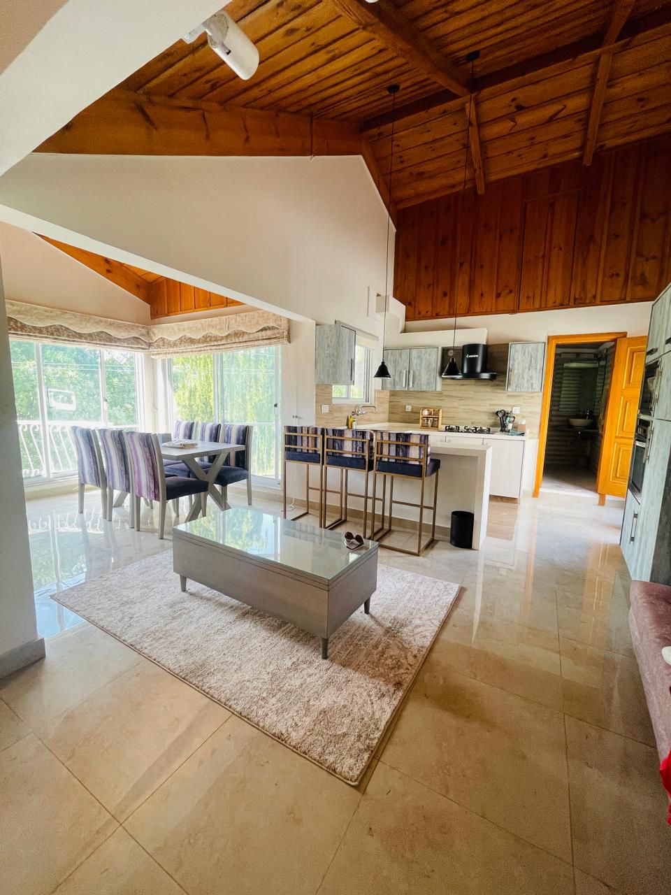 luxury cottage bedroom with en-suite bathroom, king bed, mountain view through large windows, elegant interior design, natural light