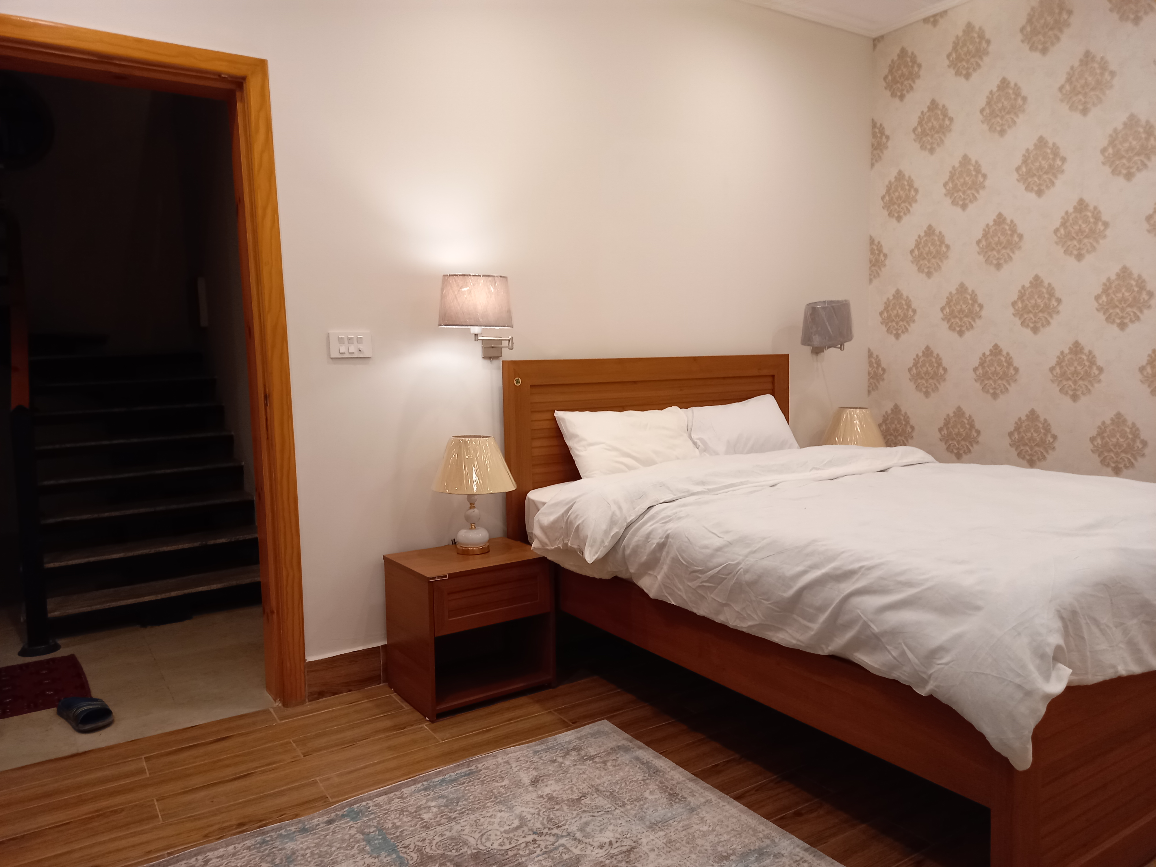 luxury cottage master bedroom with king bed, mountain view through large windows, elegant interior design, warm lighting
